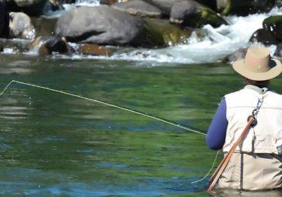 A fisherman fly fishes for Trout fish in Tongariro river near Taupo lake, New Zealand.